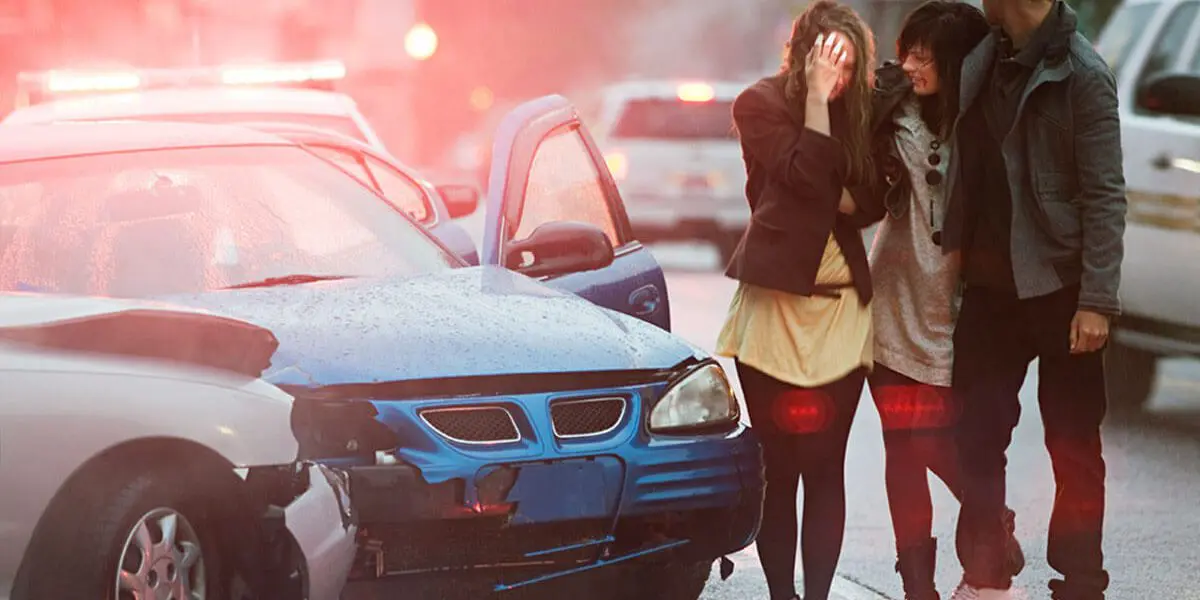 Friends embracing at accident scene after getting out of car and witnessing damage from car accident