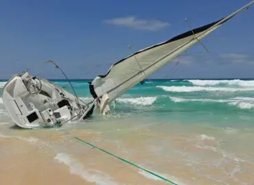 beached sail boating accident on the shore of the ocean.