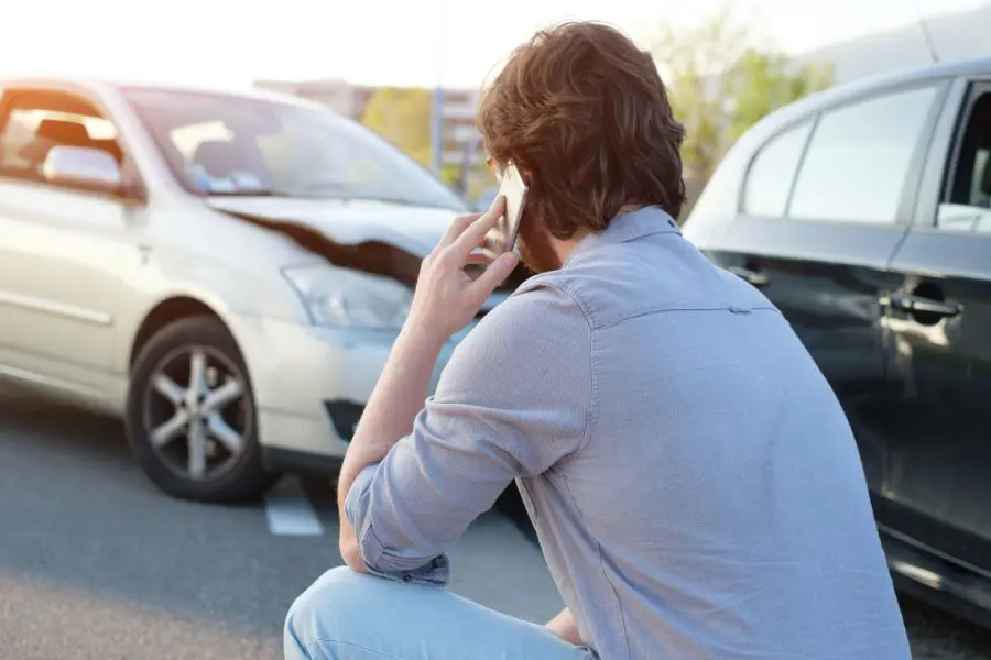 Víctima de accidente mirando daños en el coche después del accidente