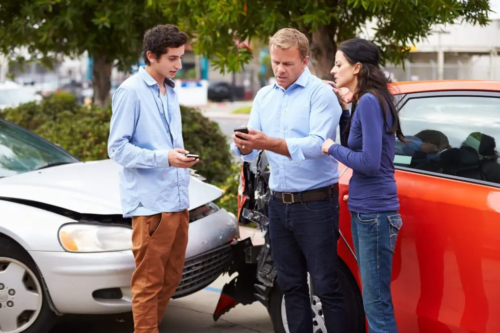 three people talking at the scene of a multiple-party car accident
