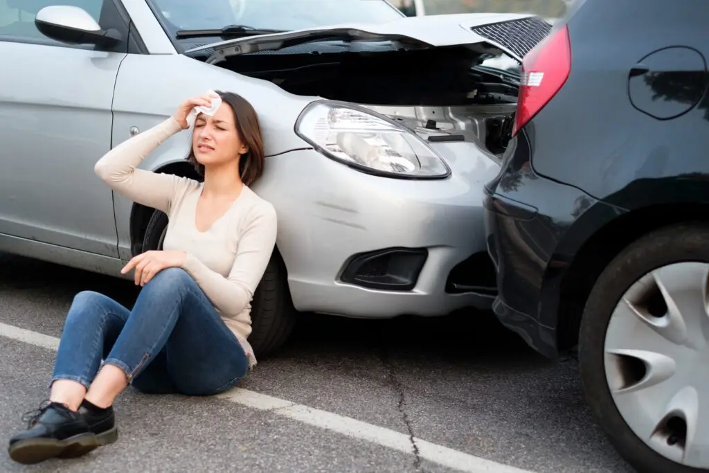 Girl sitting next to car at accident scene