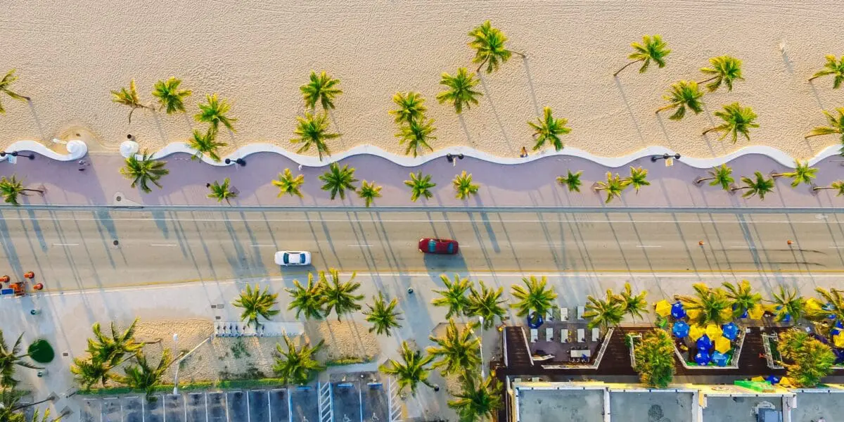 Picturesque arial view of Florida's A1A roadway with cars driving next to palm trees and beach
