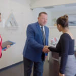 El abogado Rick Martindale en un traje azul estrechando la mano de un cliente feliz.