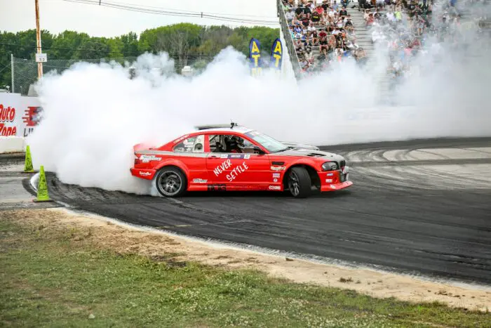 red drag racing car on track with tire smoke