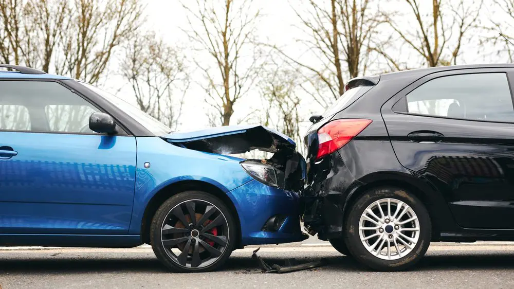 Car accident scene with a blue vehicle crashing into another car on the road