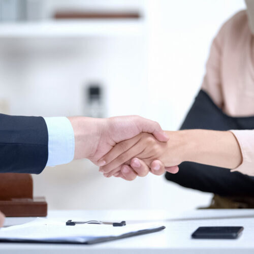 Insurance agent shaking hand with woman in arm sling, psychological support