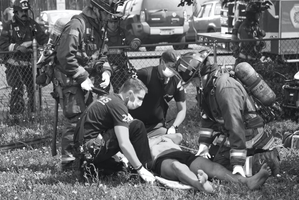 first responders assisting an injured person onto a stretcher