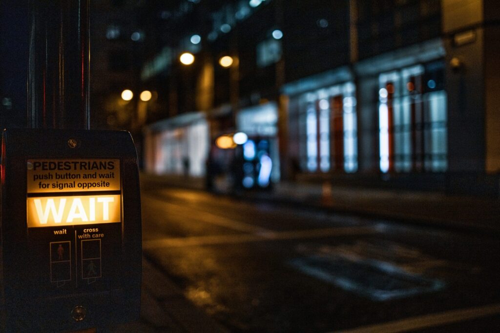 dark roadway with crosswalk sign lighting up "wait"