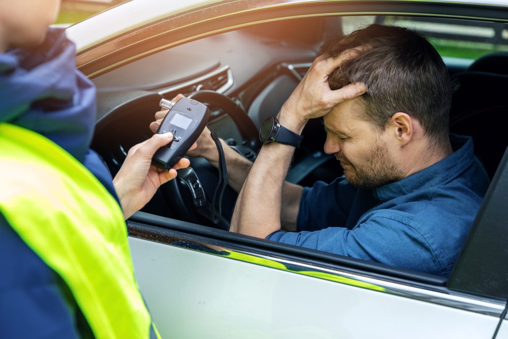 Sad drunk man sitting in a car, reflecting the dangers of drinking and driving.